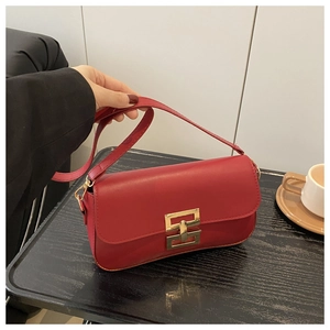 Detail of red leather crossbody bag with golden geometric clasp held by a model