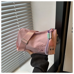 Détail du sac cylindrique en nylon rose avec broderie de lettres et large bandoulière
