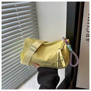 Gros plan sur le sac bandoulière en nylon jaune avec broderie et tirette tissée colorée