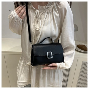 Detail of a chic black leather crossbody bag with silver buckle and top handle straps