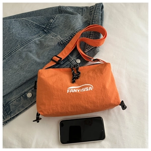 Orange nylon crossbody bag shown with a smartphone for size reference and scale