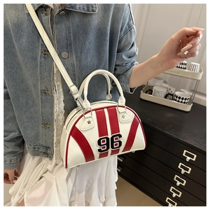 Détail du sac bowling blanc avec rayures rouges, patch numéro 96 et rivets en étoile