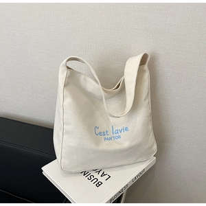 Gros plan sur un sac cabas en toile blanche avec inscription artistique C'est la vie