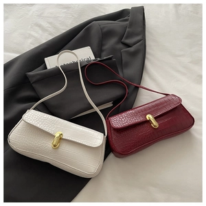 Detail of crocodile pattern underarm bags in ivory and burgundy with gold locks