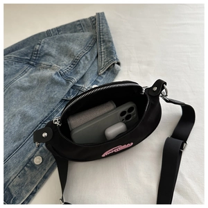 Détail du sac bandoulière noir montrant la capacité pour téléphone et accessoires