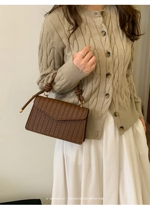 Detail of dark brown woven texture handbag with retro minimalist fold-over flap design
