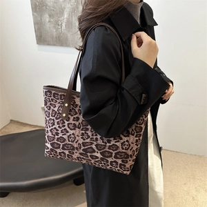 Leopard print tote bag with brown leather handles worn by model in minimalist studio
