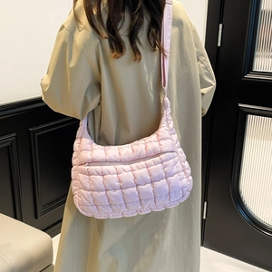Chic pink quilted puffer tote bag with adjustable strap worn by model in a minimalist setting