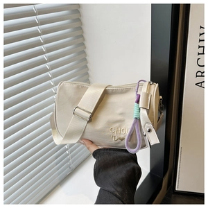 Détail du sac Boston crème avec broderie coeur et lanière tressée violette élégante