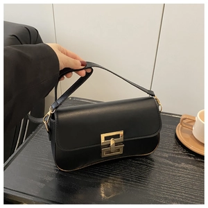 Detail of a minimalist black leather crossbody bag with a modern gold geometric buckle