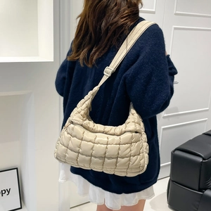 Quilted cream puffer shoulder bag with adjustable strap shown on model's back