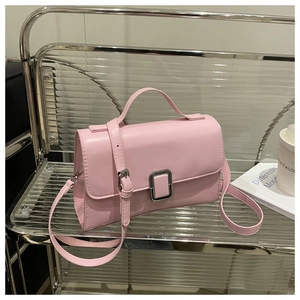Detail of light pink PU leather bag with silver metal clasp and top handle on a display stand