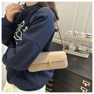 Dettaglio della borsa beige con chiusura ovale dorata e trama in pelle martellata sul modello