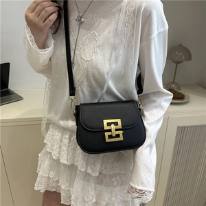 Classic black square crossbody bag with gold buckle on a model in casual setting