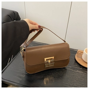 Close-up of vintage brown leather underarm bag with gold geometric clasp and wide strap