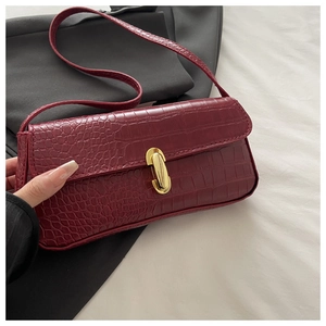Close-up of burgundy crocodile pattern baguette bag with premium gold metallic clasp