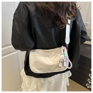 Vue détaillée du sac polochon en toile beige avec broderie CHOU et pendentif tissé chic