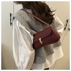 Dettaglio borsa sottobraccio in pelle bordeaux con elegante chiusura a scatto dorata