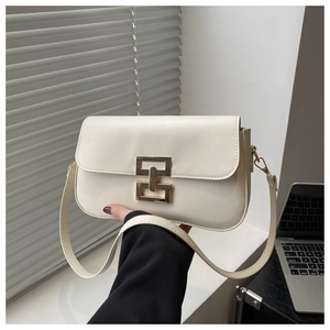 Detail of cream rectangular shoulder bag with golden geometric clasp in office setting
