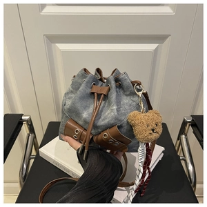 Detail of vintage washed denim bucket bag with brown leather drawstring and bear charm
