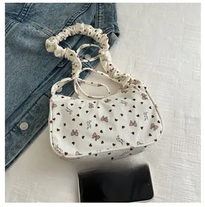 Size comparison of white corduroy heart print handbag with phone on denim background