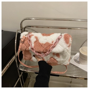 Détail du sac en peluche rose à motif vache avec texture matelassée et chaîne décorative