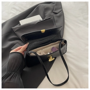 Detail of black crocodile texture baguette bag interior showing storage capacity and golden lock