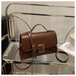 Detailed view of a brown vintage square bag with a silver buckle on a metal cart