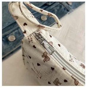 Detail of smooth silver zipper on beige corduroy bag with heart and bow patterns