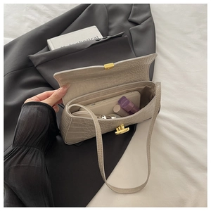 Detail view of the open beige crocodile pattern bag showing spacious interior and gold clasp