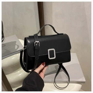 Detail of black matte leather square bag featuring a silver metal buckle and handle