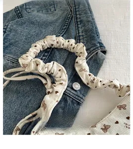 Detailed shot of white corduroy mini bag featuring floral bow prints and ruffled handle