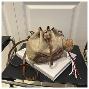 Detail of vintage khaki canvas bucket bag with brown faux leather straps and plush bear charm