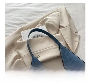Close-up of deep blue leopard print tote bag with logo detail on a beige blazer