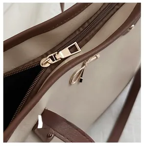 Detailed macro view of smooth golden metal zipper and elegant leather trim on the tote bag