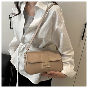 Detail of light brown crossbody bag with gold metal clasp on model in minimal interior