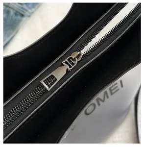 Detailopname van de metalen rits en lederen textuur van een zwarte minimalistische tas