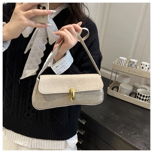Close-up of off-white faux crocodile leather baguette bag with a gold metal lock