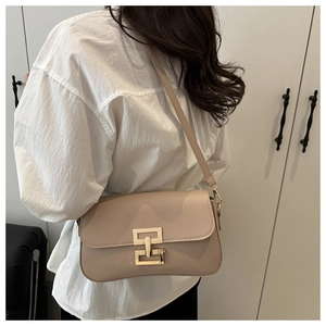 Side view of a beige crossbody bag with golden geometric lock and adjustable strap