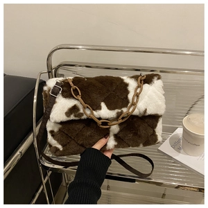 Détail du sac à main peluche à motif vache avec texture matelassée et chaîne acrylique