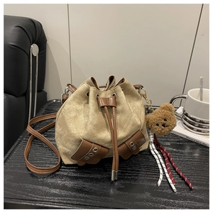 Detail of khaki canvas bucket bag with brown faux leather trim and plush bear charm