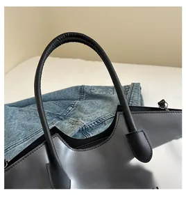 Detail van zwarte glanzende handtas met ronde leren handvatten en golvende randen