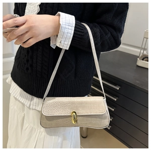 Detail of light gray crocodile pattern baguette bag with a golden metal rotary lock