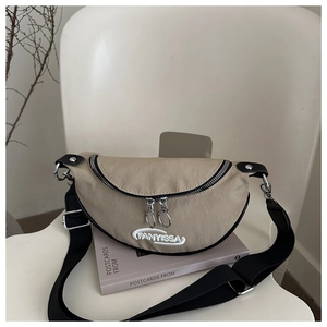 Détail du sac bandoulière demi-lune kaki avec broderie FANYISSA blanche et sangle