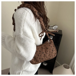 Detail of dark brown corduroy shoulder bag featuring black bows and heart patterns