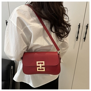 Detail of red crossbody bag featuring a golden geometric buckle worn with white shirt
