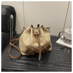Detail view of the drawstring bucket bag featuring retro canvas and brown leather trim