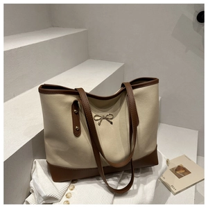 Detail of minimalist tote bag with metal bow and brown trim on white background