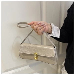 Close-up of beige crocodile pattern baguette bag with a vintage gold oval metal buckle
