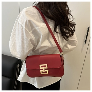 Side view of a red matte leather crossbody bag with a gold geometric clasp on a model